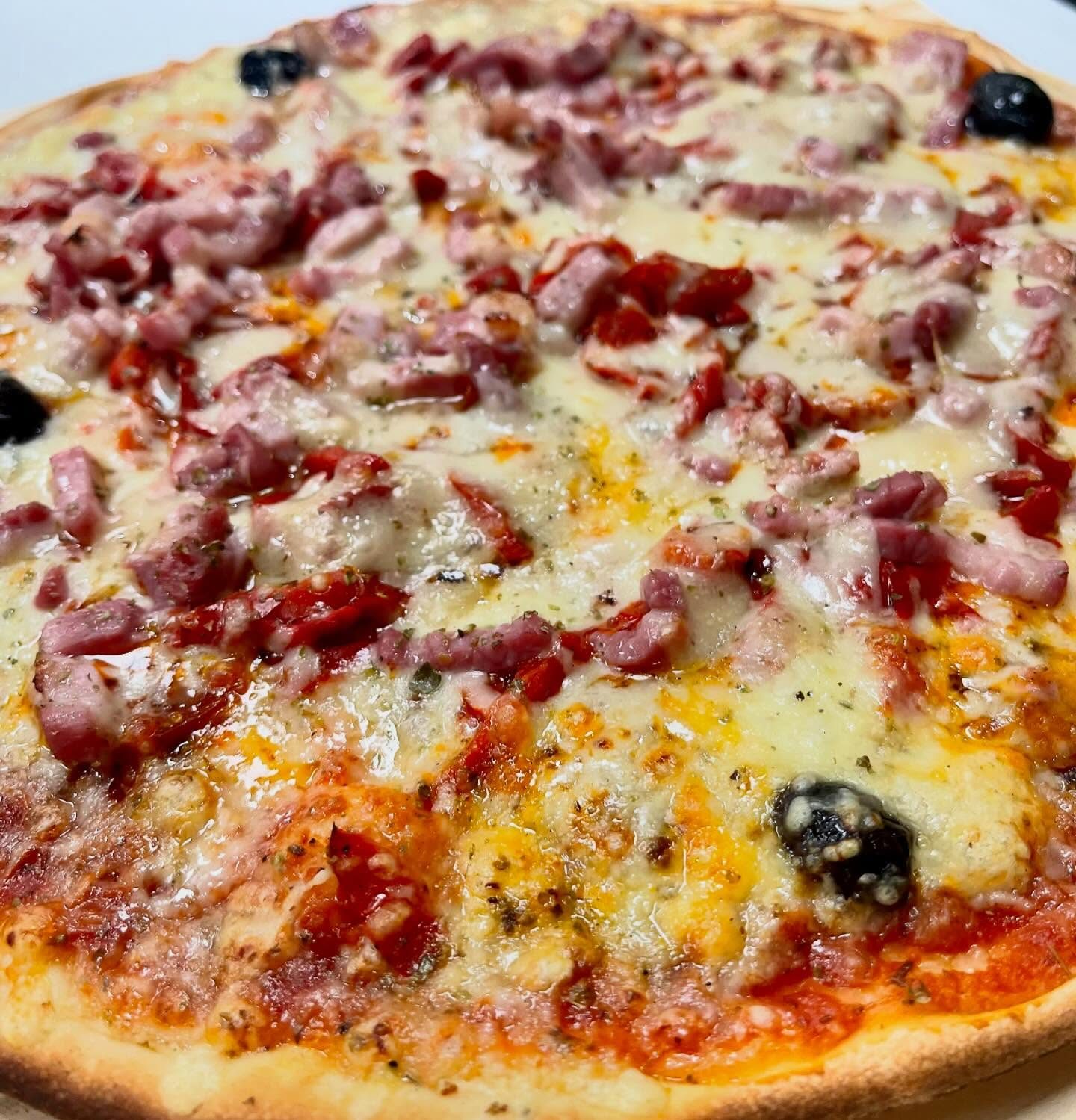 Pizza garnie sortie du four chez Pizza Gilbert